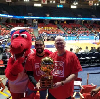 Dean Bo Fernhall, PT student Josuf Robinson and Sparky D. Dragon pose with the Challenge of the Deans championship trophy
                  