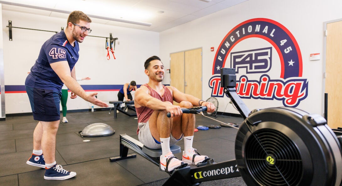 A F45 Coach motivates a student on the rowing maching